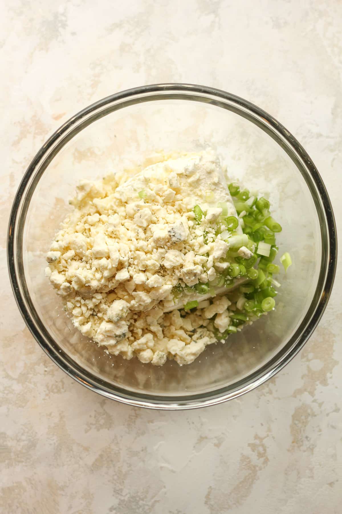 A bowl of the chicken filling mixture - cream cheese, blue cheese, and chopped green onions.