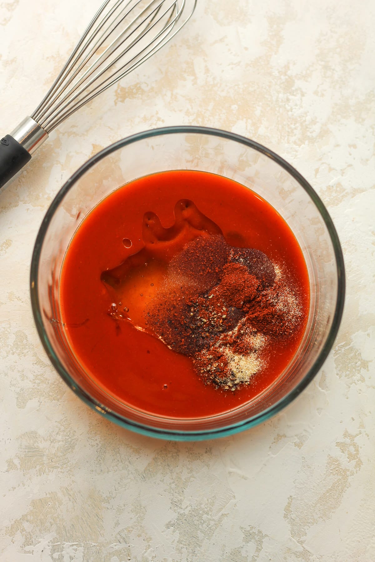 A bowl of the buffalo sauce with a whisk.