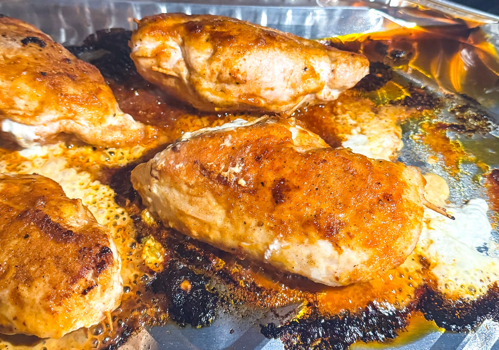 The just grilled buffalo chicken breasts in a disposable pan.