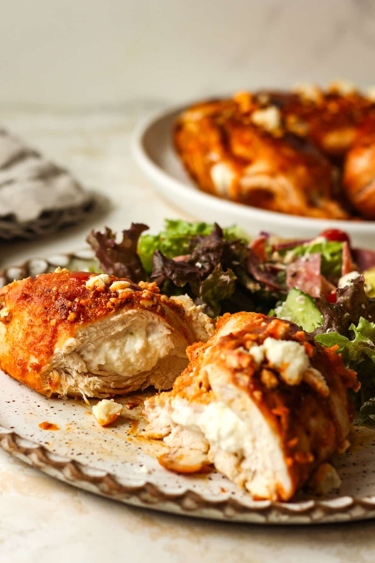 Side view of a stuffed chicken breast topped with buffalo sauce.