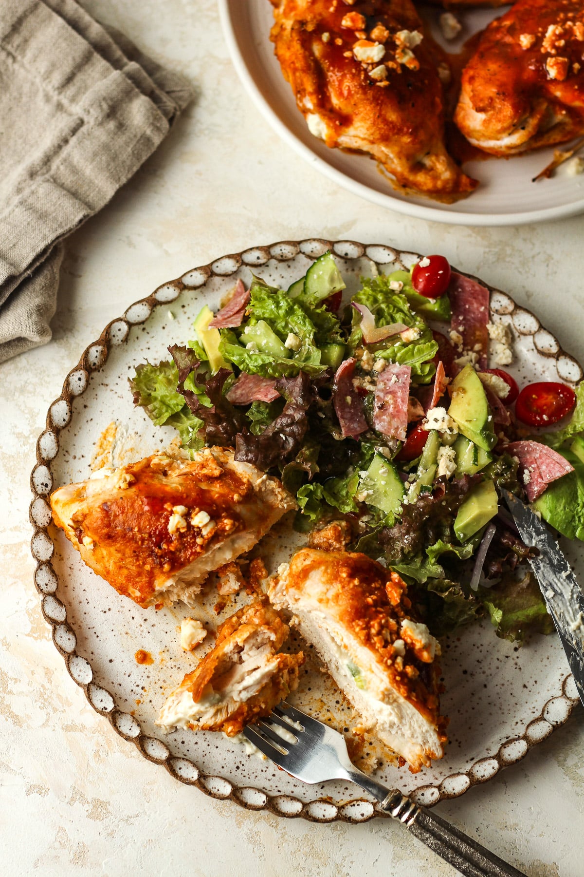 Overhead view of a plate with a buffalo chicken breast stuffed with cheese and a salad.