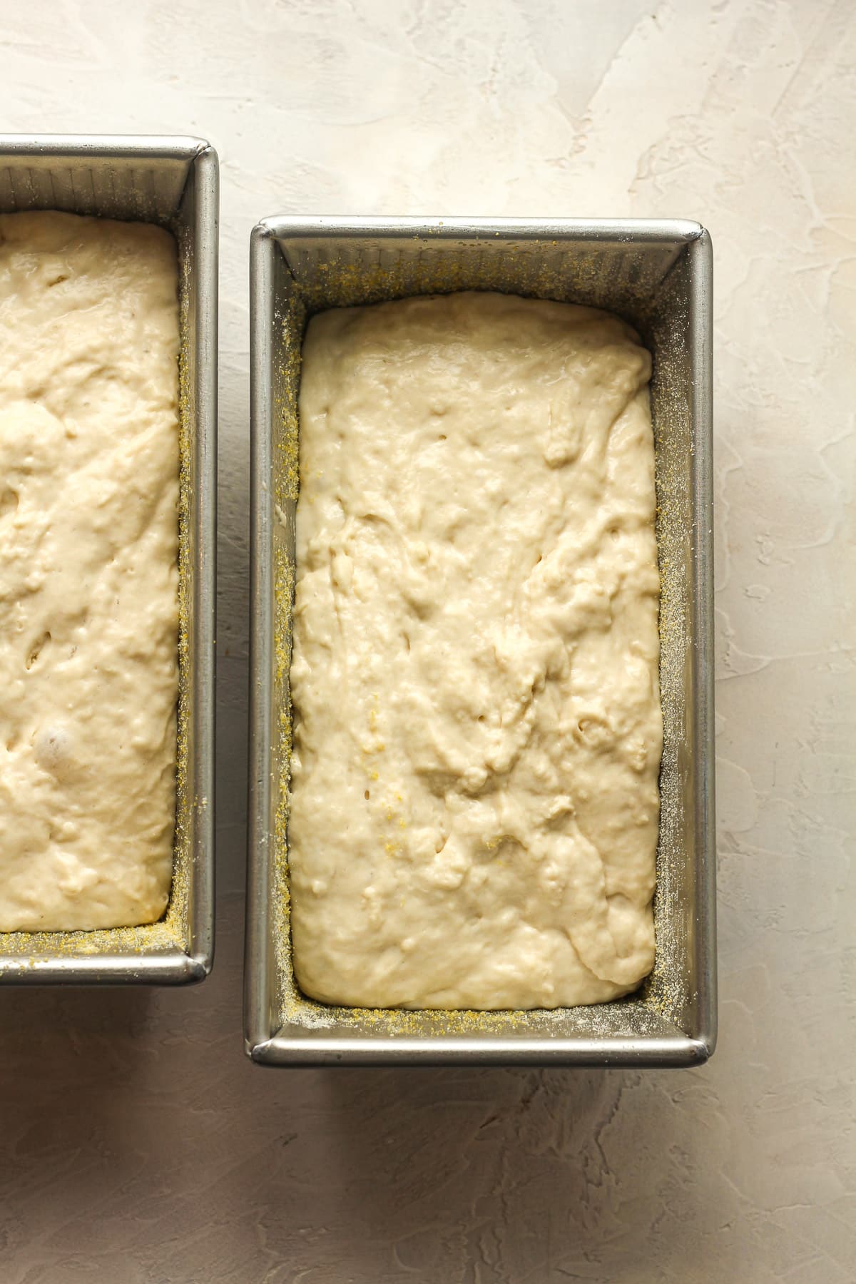 Overhead view of two loaf pans with the runny dough.