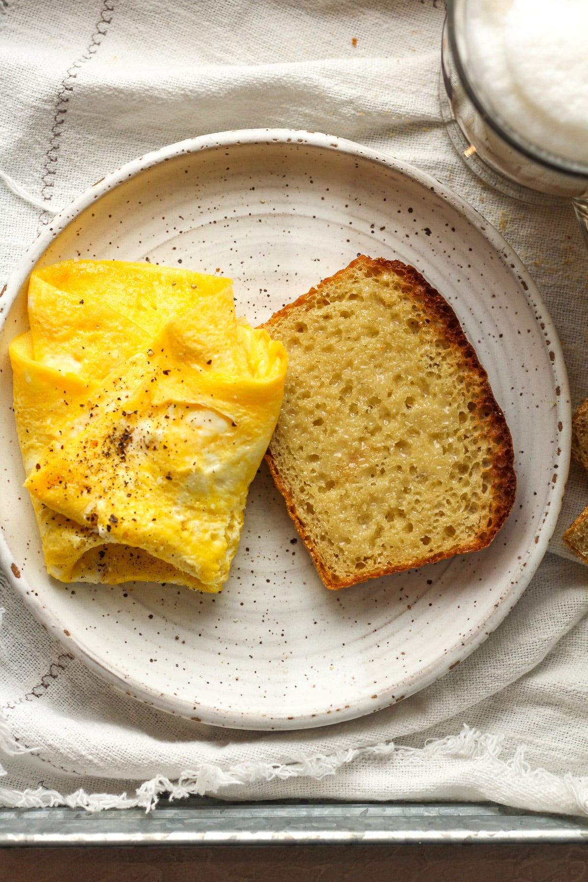 A plate with a slice of English muffin bread and two scrambled eggs.