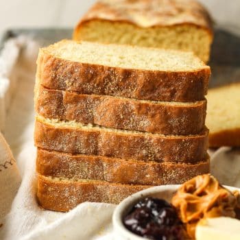 Stacked English muffin bread with a small bowl of peanut butter and jelly.