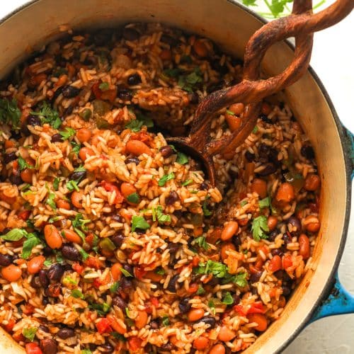 Overhead view of a stock pot of Mexican rice and beans with a wooden spoon.