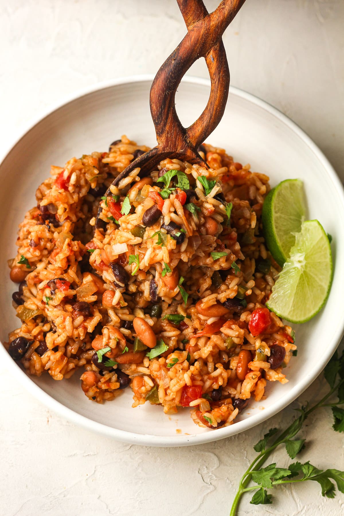 Overhead view of a wooden spoon adding Mexican rice to a plate.