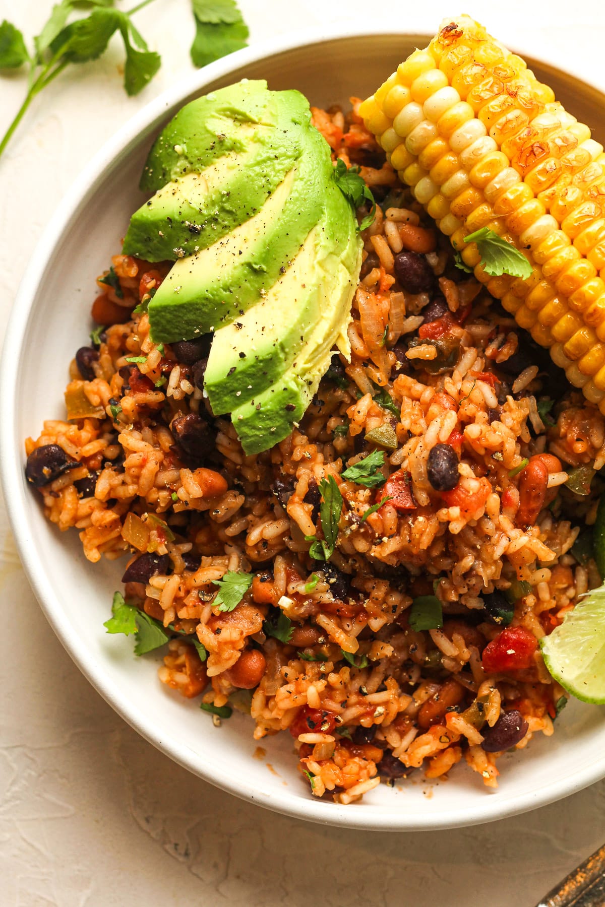 A bowl of Mexican rice and beans with sliced avocado.