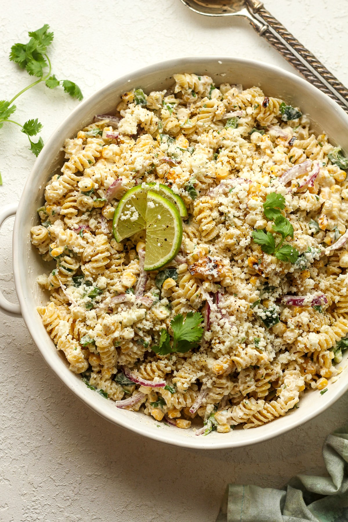 Overhead view of a round salad bowl of Mexican street corn pasta salad with cotija cheese.