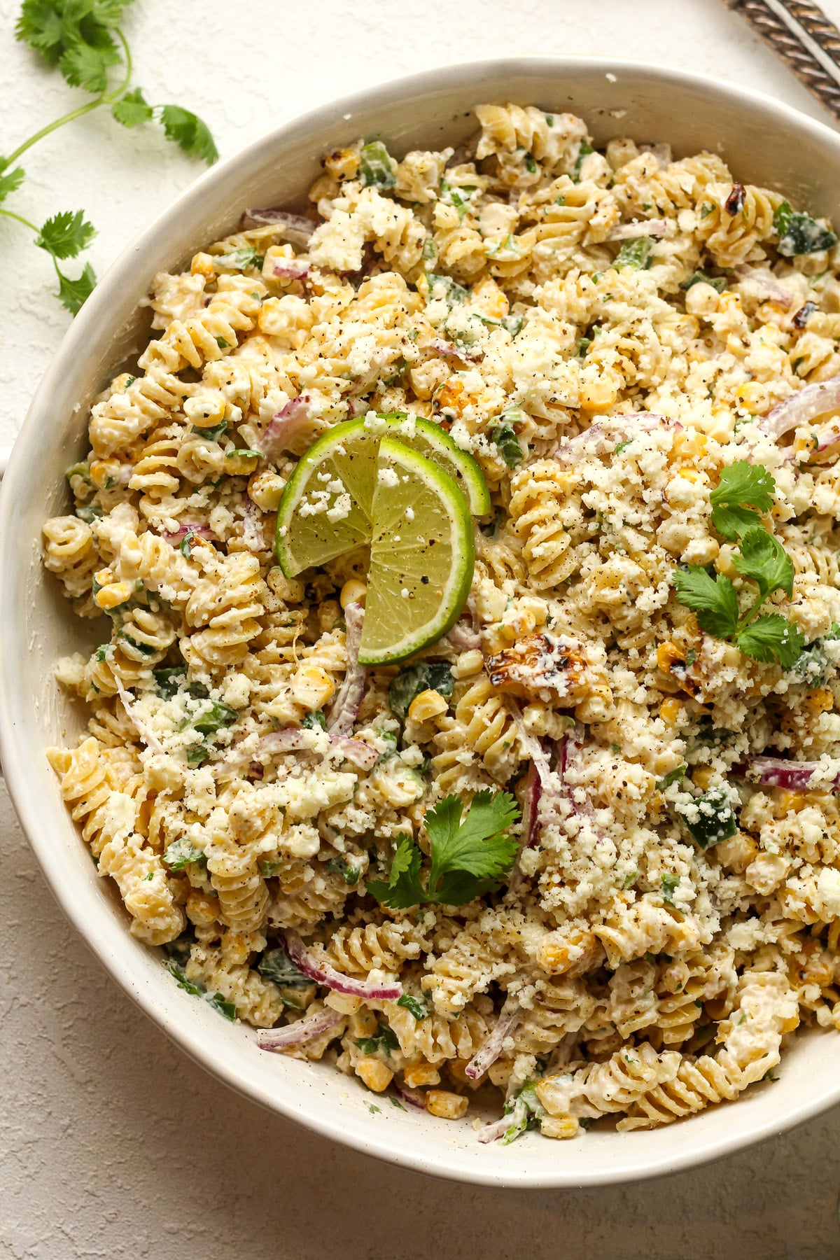 A round dish of Mexican street corn salad with pasta.