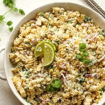 Closeup on a bowl of Mexican street corn pasta salad with lime slices.