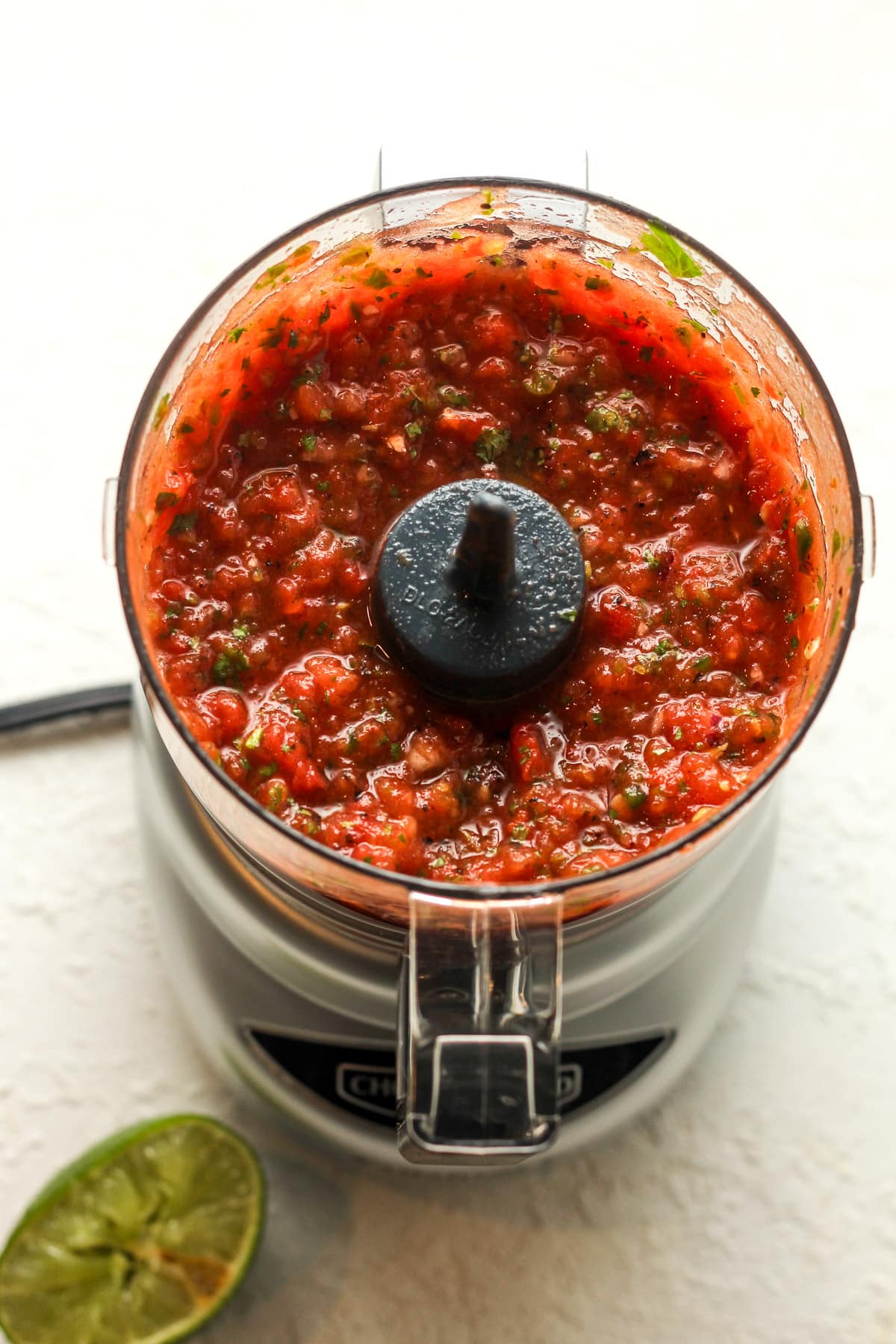 Overhead view of a mini food processor after blending the salsa ingredients.