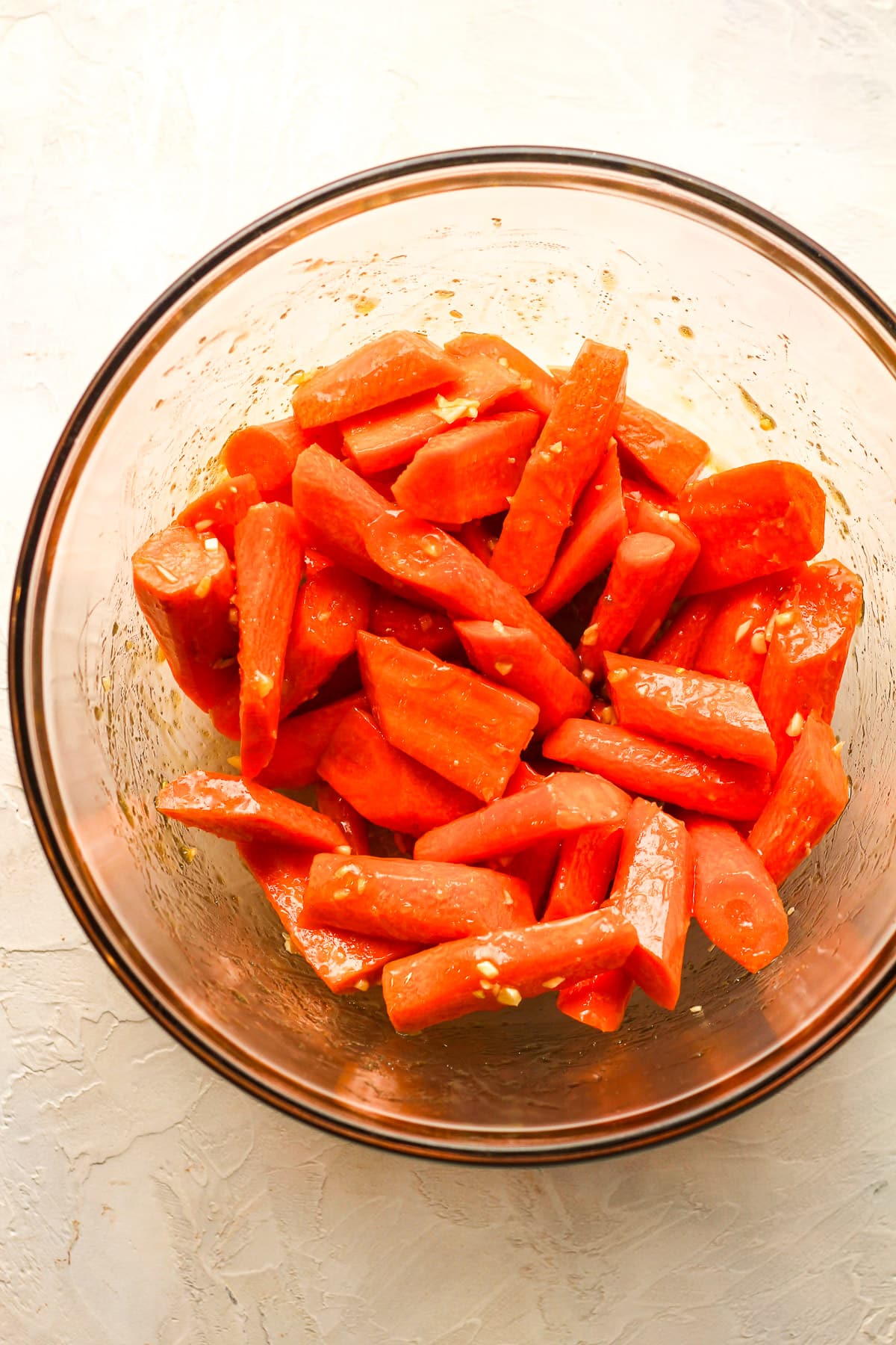 A bowl of the prepped carrots after adding the liquid mixture.