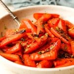 Side view of a bowl of honey roasted carrots with brown sugar.