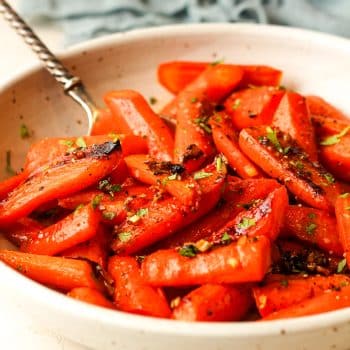 Side view of a bowl of honey roasted carrots with brown sugar.