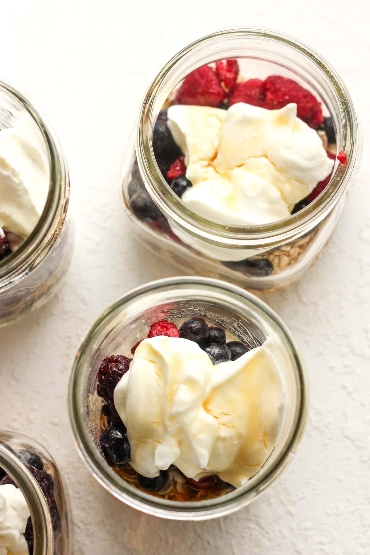 Overhead shot of several jars of oats after adding the fruit, yogurt and maple syrup.