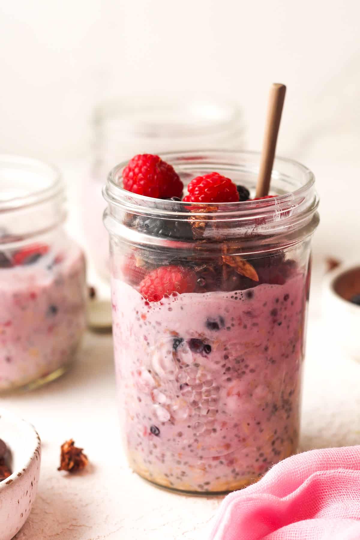 Side view of a jar of frozen berry overnight oats with fresh fruit on top.