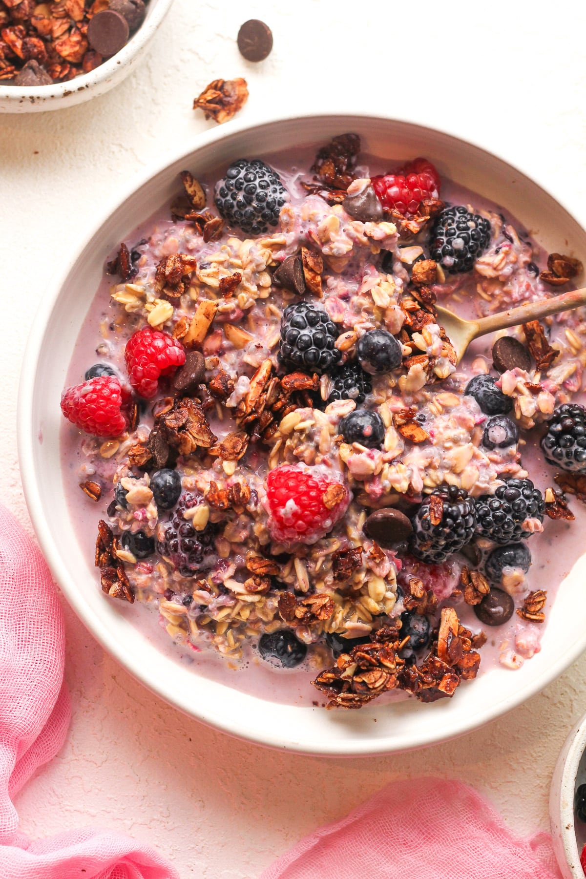 A bowl of overnight oatmeal with frozen berries plus granola on top.