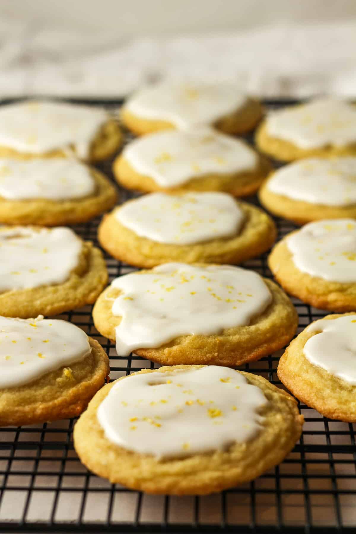 Side view of a cooling rack with glazed lemon sugar cookies.