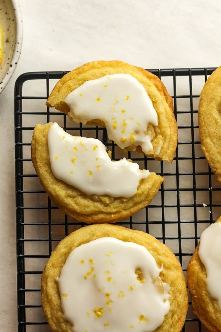 Lemon sugar cookies on a cooling rack with one broken in half.