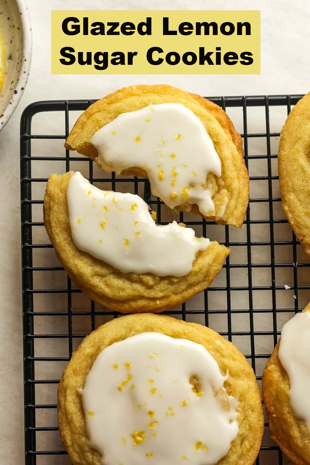 Closeup on a glazed lemon sugar cookie broken in half on a wire rack.