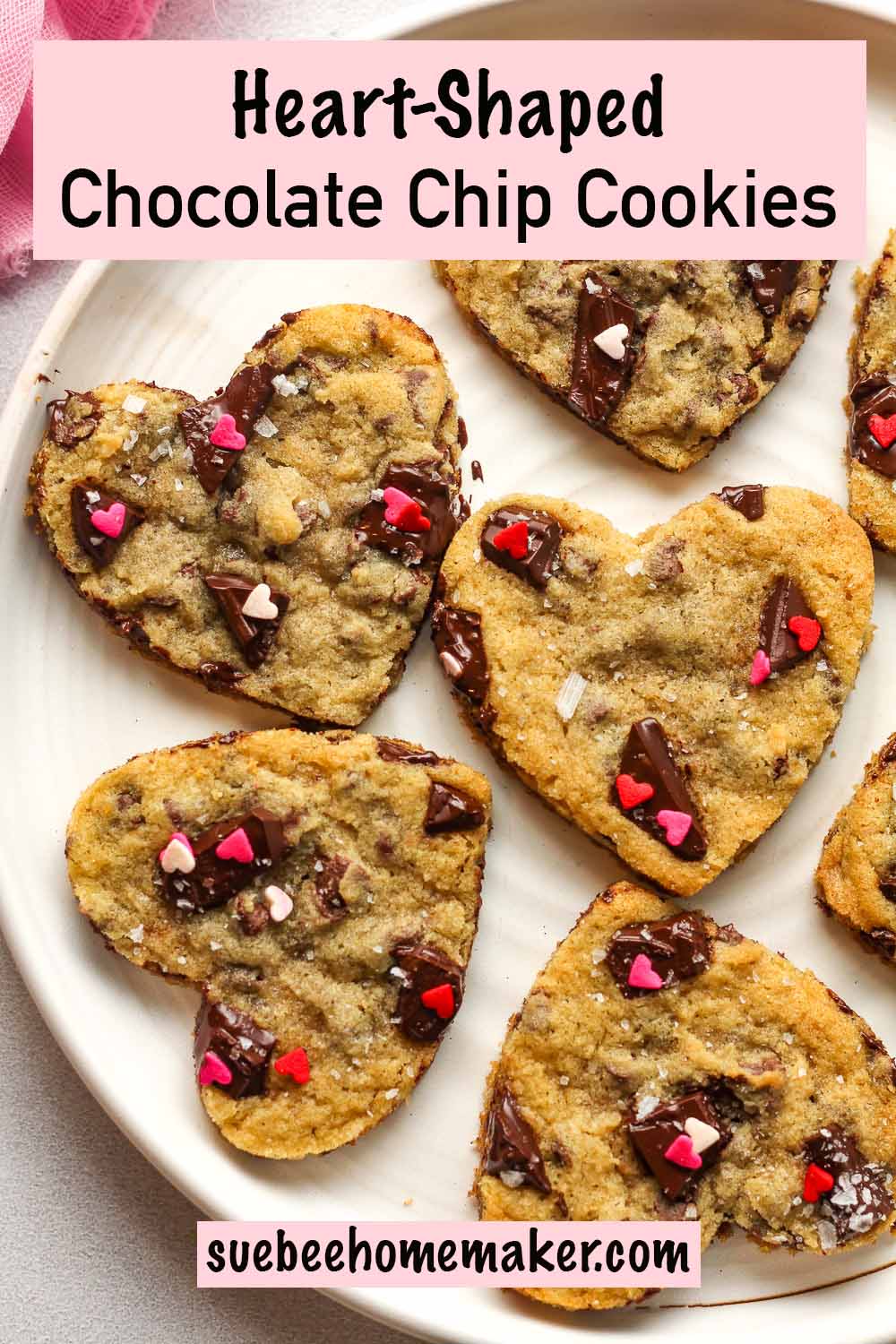 A plate of heart-shaped chocolate chip cookies with sprinkles on top.