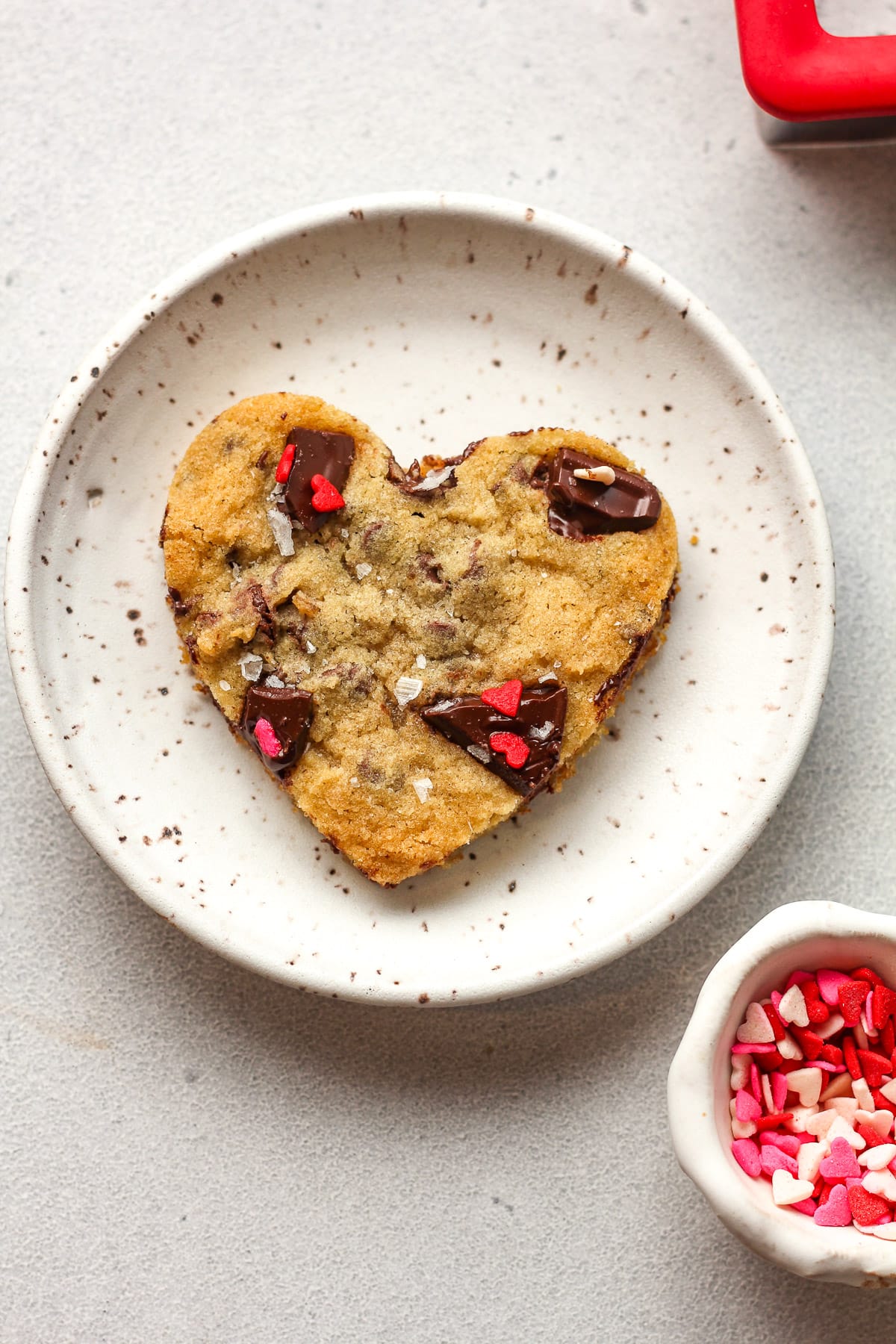 A small plate with a heart-shaped chocolate chip cookie.