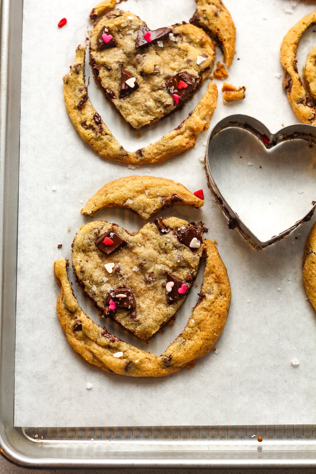 Closeup on a try of chocolate chip cookies being cut out with cookie cutter.