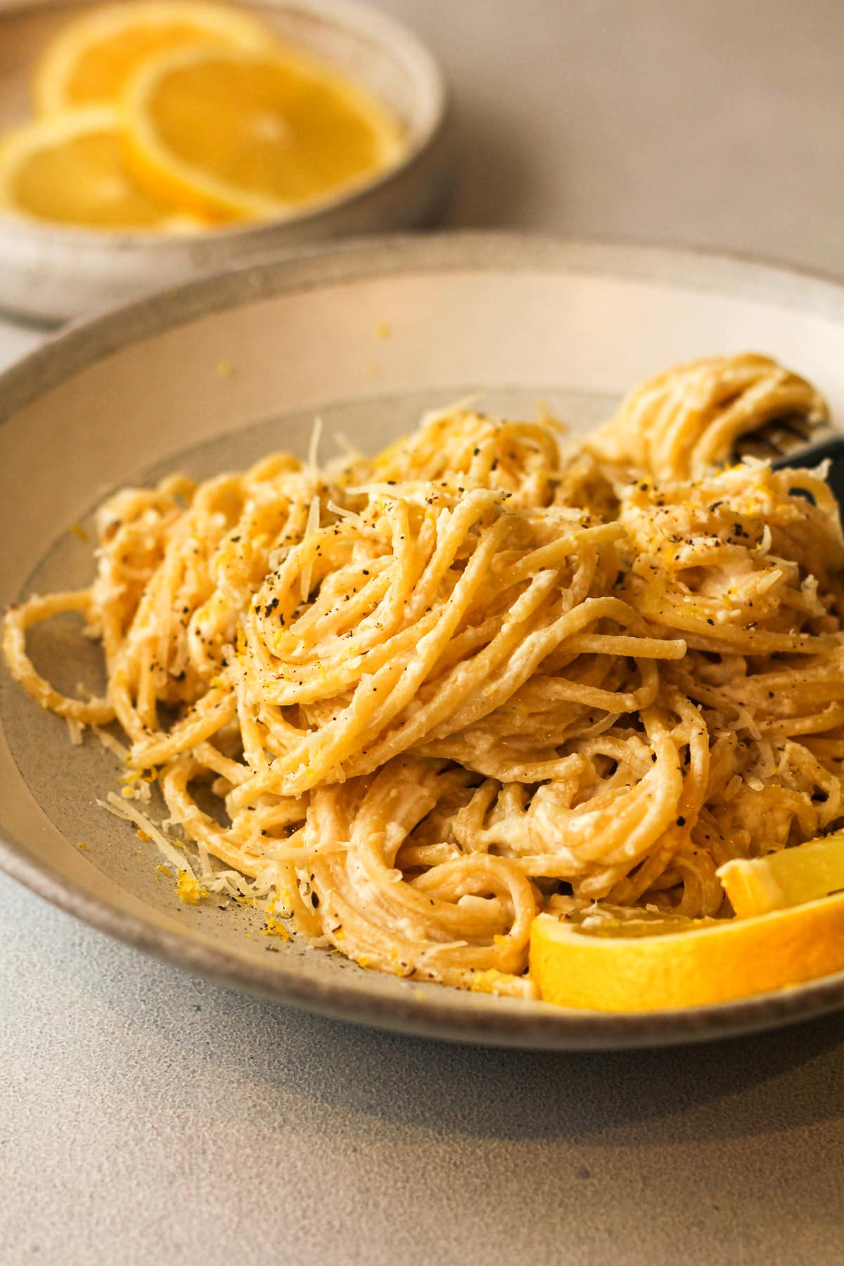 Side view of a bowl of lemon ricotta pasta with lemon slices.