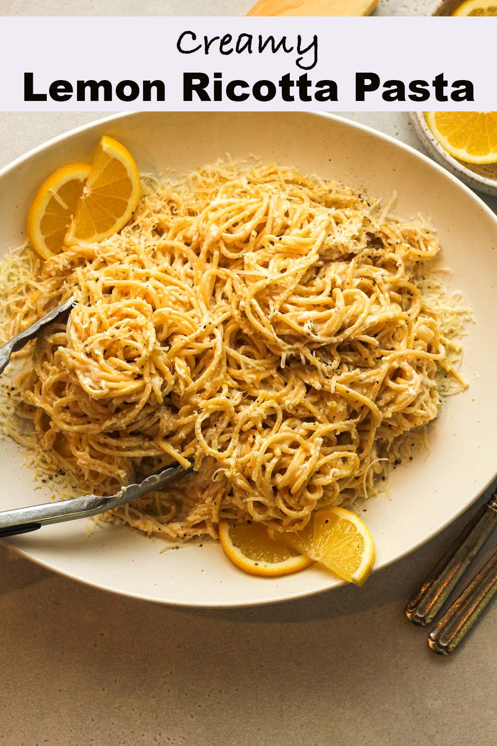 A platter of creamy lemon ricotta pasta with lemon slices.