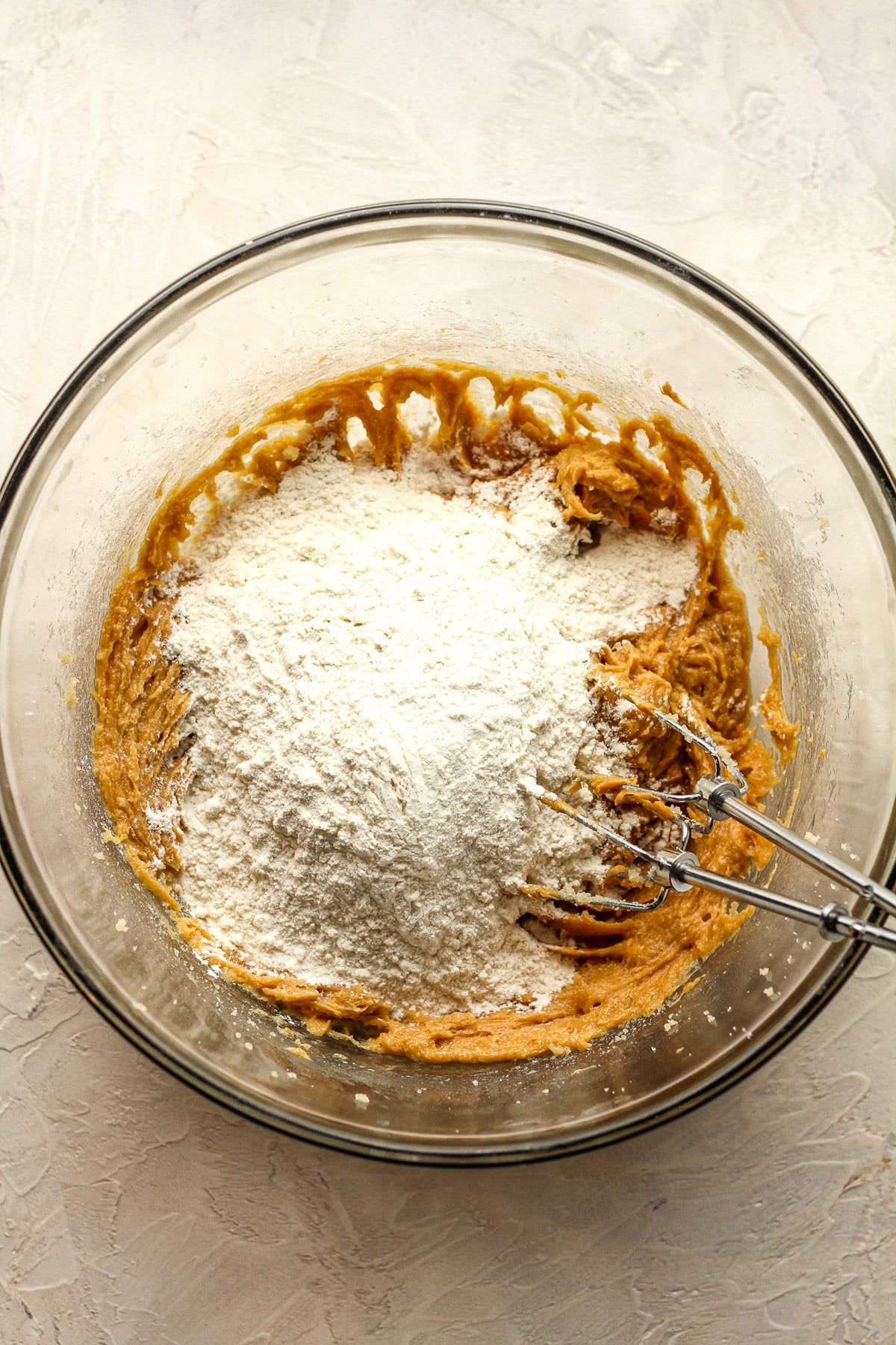 A bowl of the wet cookie ingredients with the dry on top.