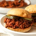 Side view of a plate of two spicy sloppy joes in soft buns.