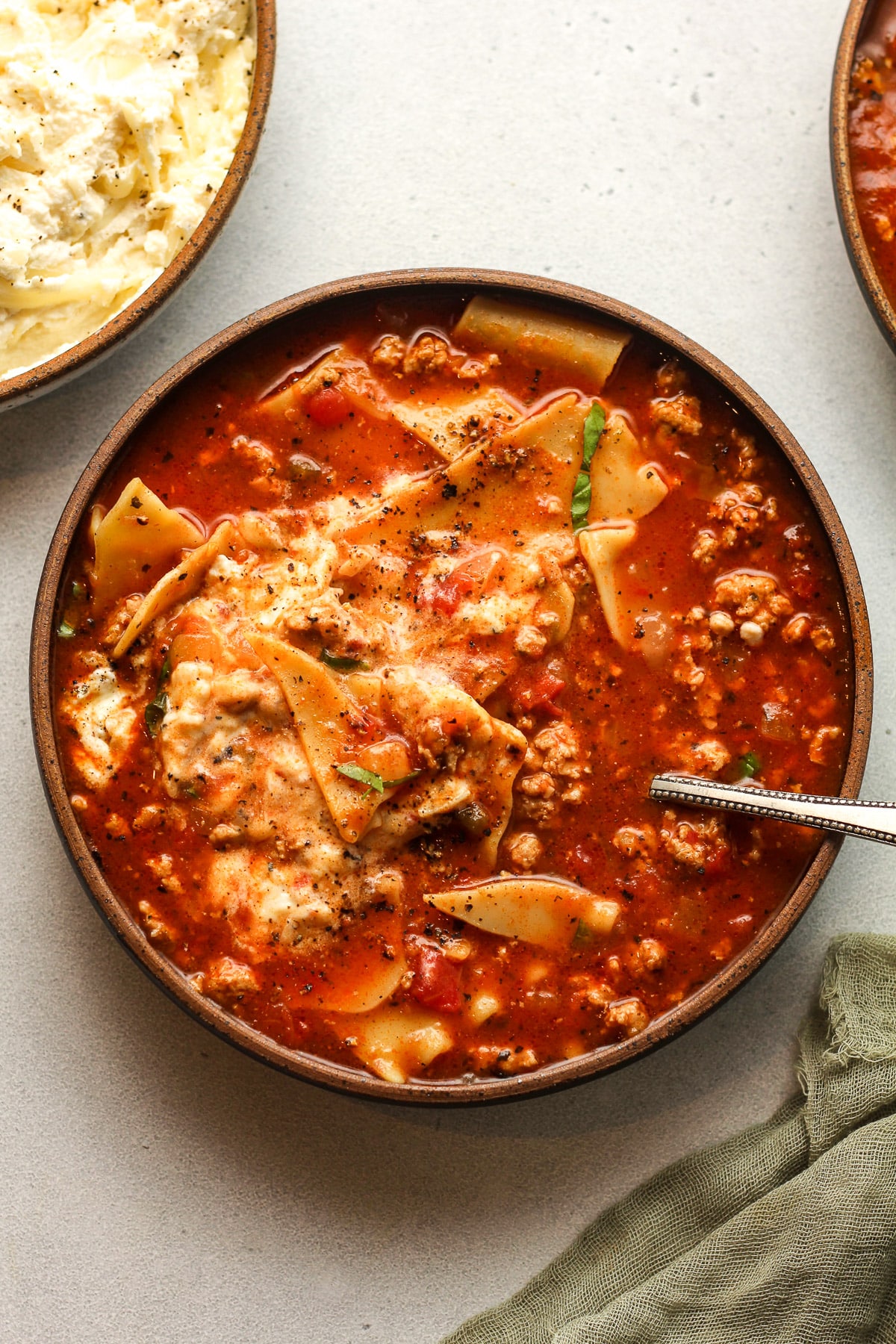 A bowl of turkey lasagna soup with the cheese blend mixed in.