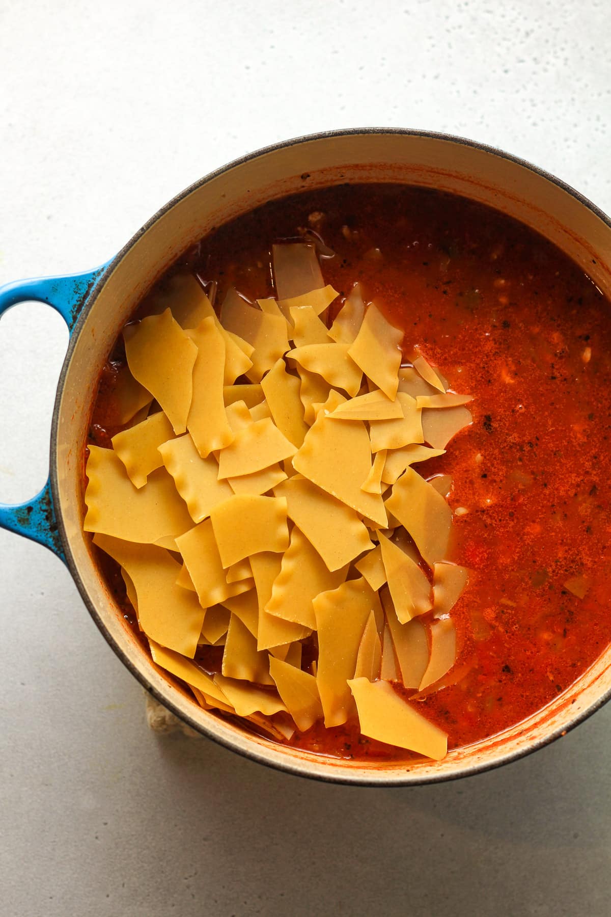 A pot of the soup with the broken up lasagna noodles on top.