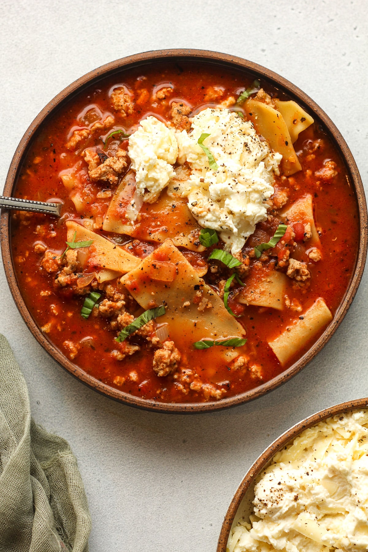 Overhead view of a bowl of turkey lasagna soup with ricotta mixture.