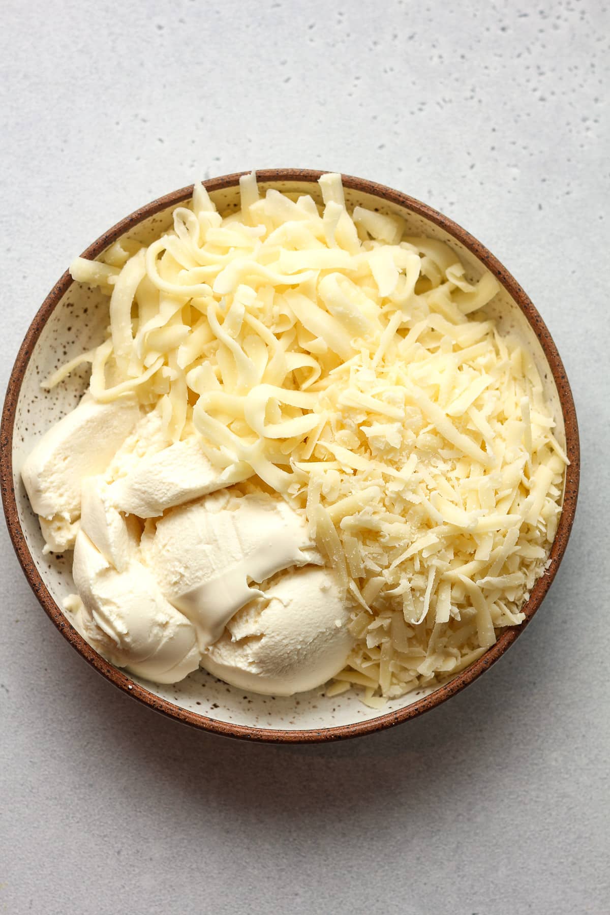 A bowl of three kinds of cheese - ricotta, mozzarella, and parmesan.