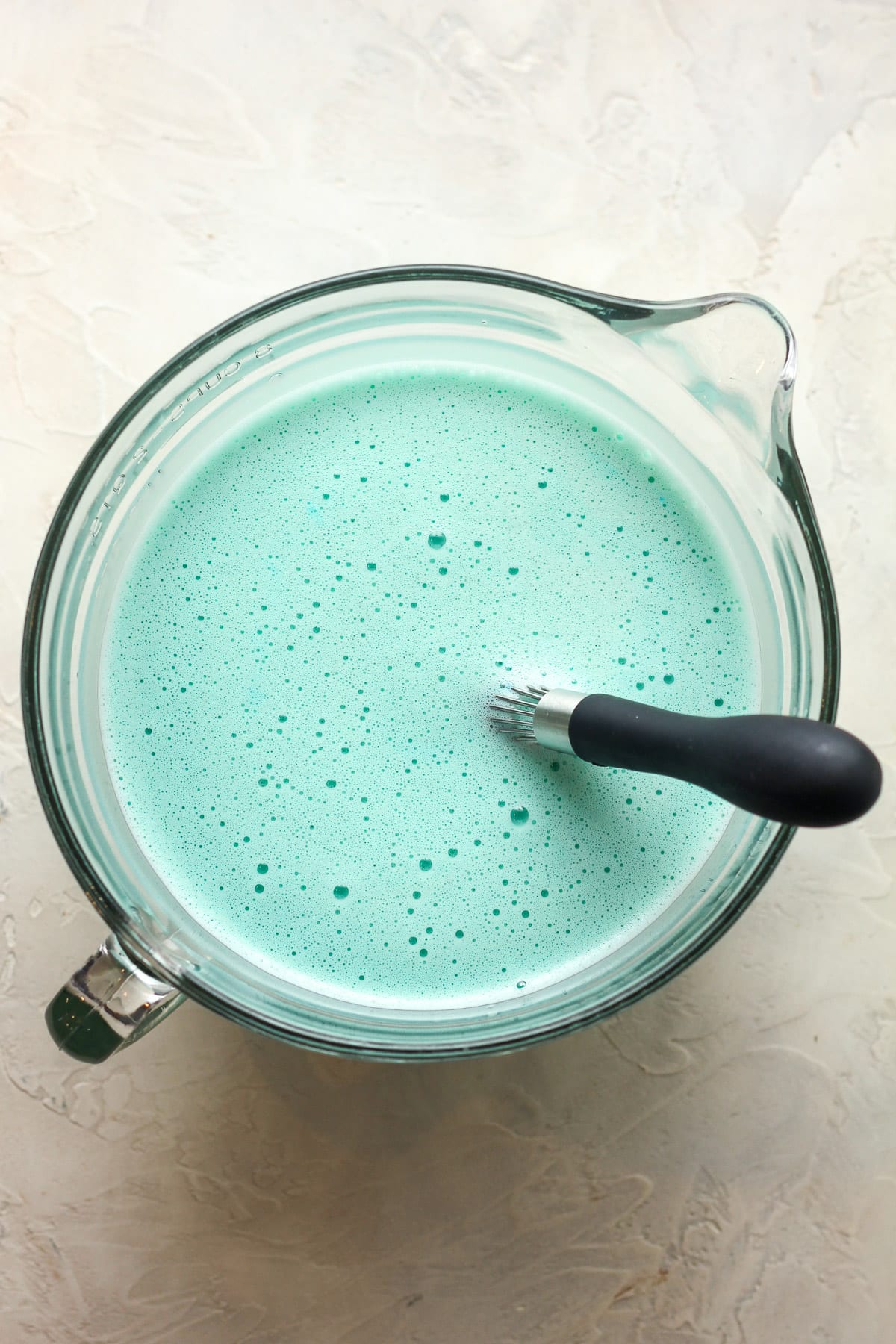 A large measuring bowl of the vanilla base liquid tinted blue.