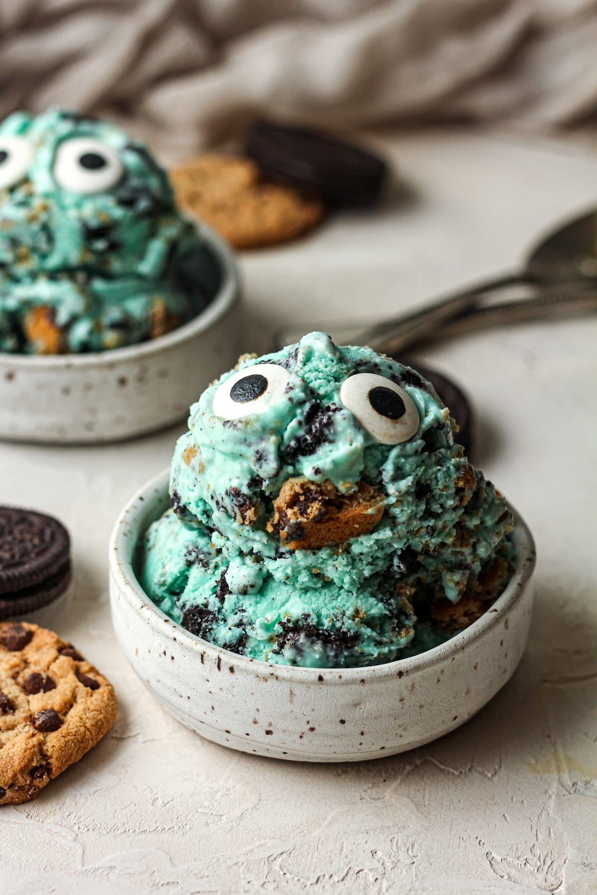 Side view of two small bowls of Cookie Monster ice cream with large eyeballs.