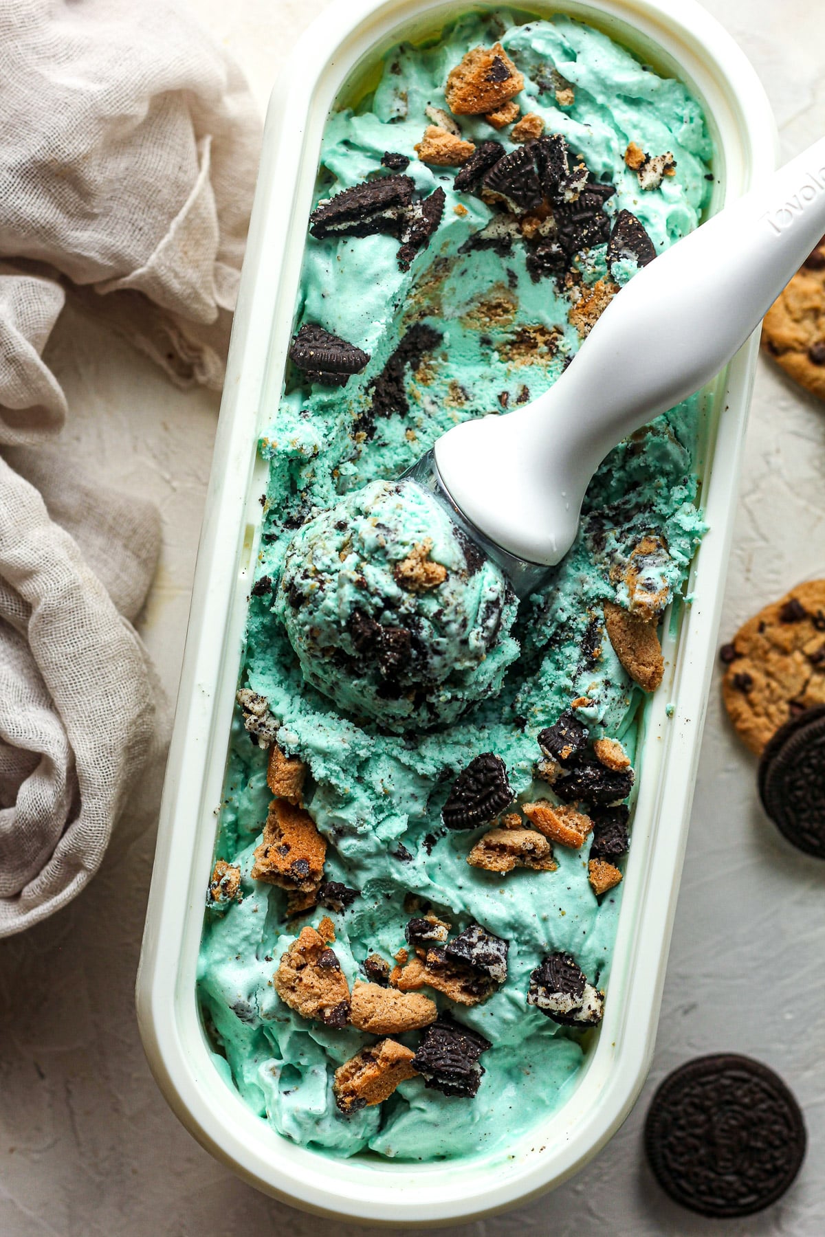 Overhead view of a white container filled with Cookie Monster ice cream with a scoop inside.