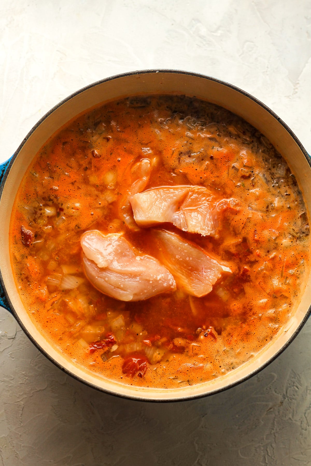 A stock pot with the raw chicken added in.