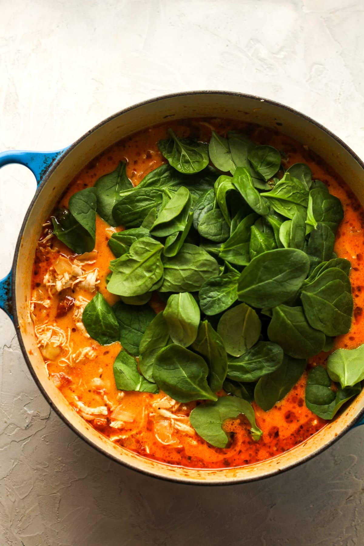 A stock pot of the soup after adding spinach leaves.