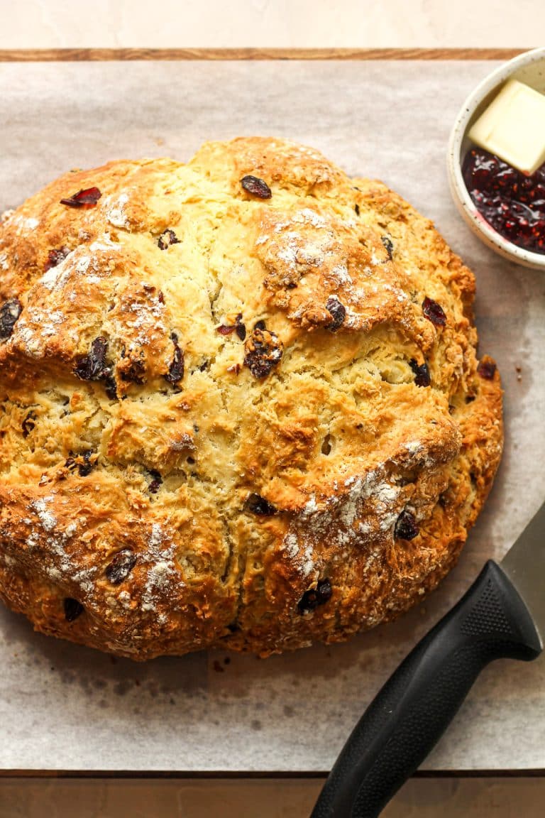 Overhead view of a loaf of Irish soda bread with a bowl of butter and jam.