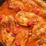 A skillet of cajun chicken with a creamy red sauce.