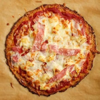 A cauliflower pizza with ham and pineapple toppings.