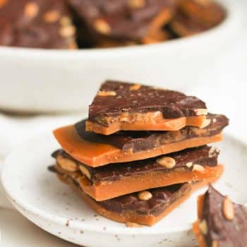 A stack of dark chocolate toffee on a small plate.