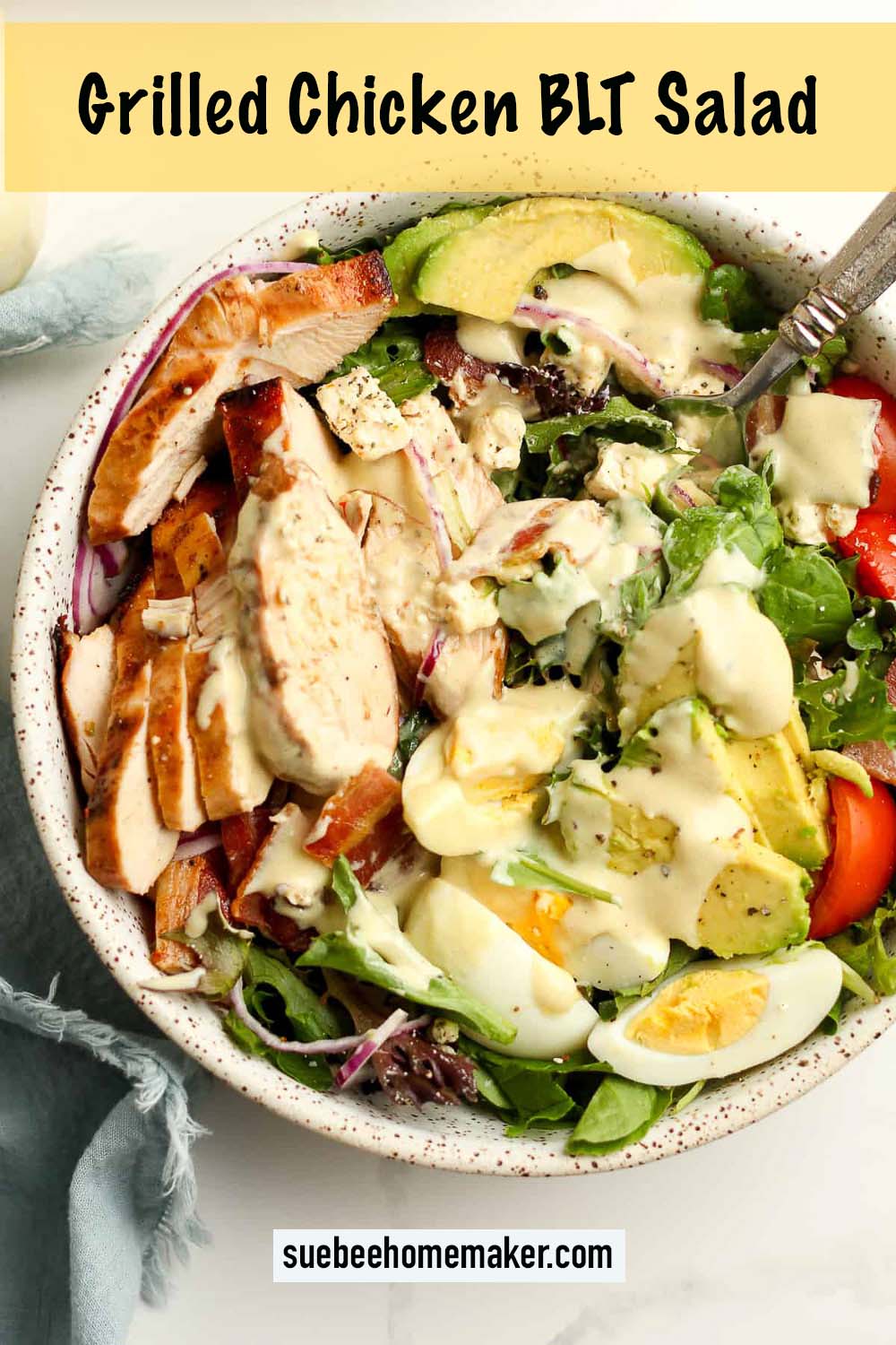 A serving bowl of grilled chicken BLT salad with honey mustard dressing.