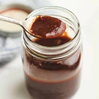 A tablespoon of barbecue sauce overtop a mason jar of sauce.