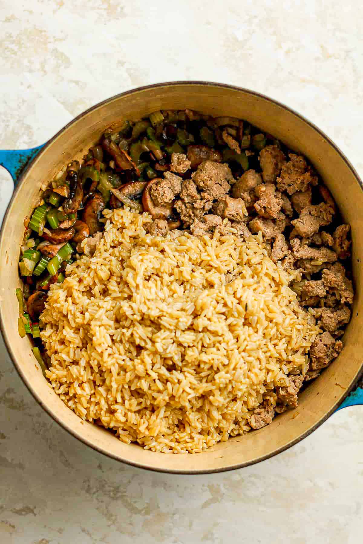 A stock pot of the veggies plus sausage and cooked rice on top.