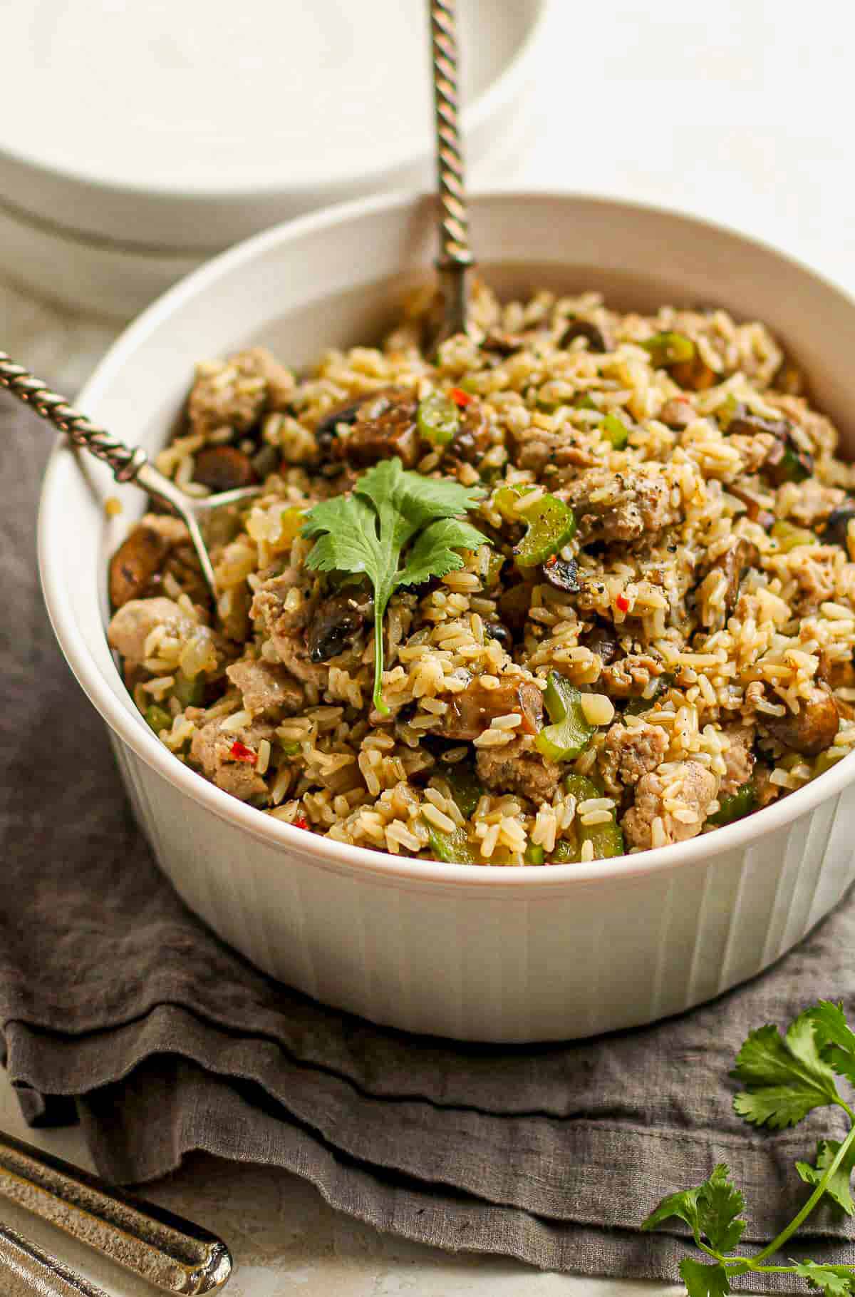 Side view of a white bowl with rice dressing and mushrooms and celery.