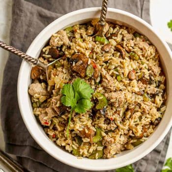 A large bowl of rice dressing with mushrooms and sausage.