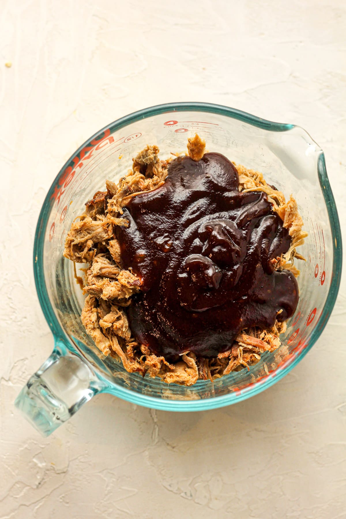 A measuring cup of the pulled pork plus the barbecue sauce on top.